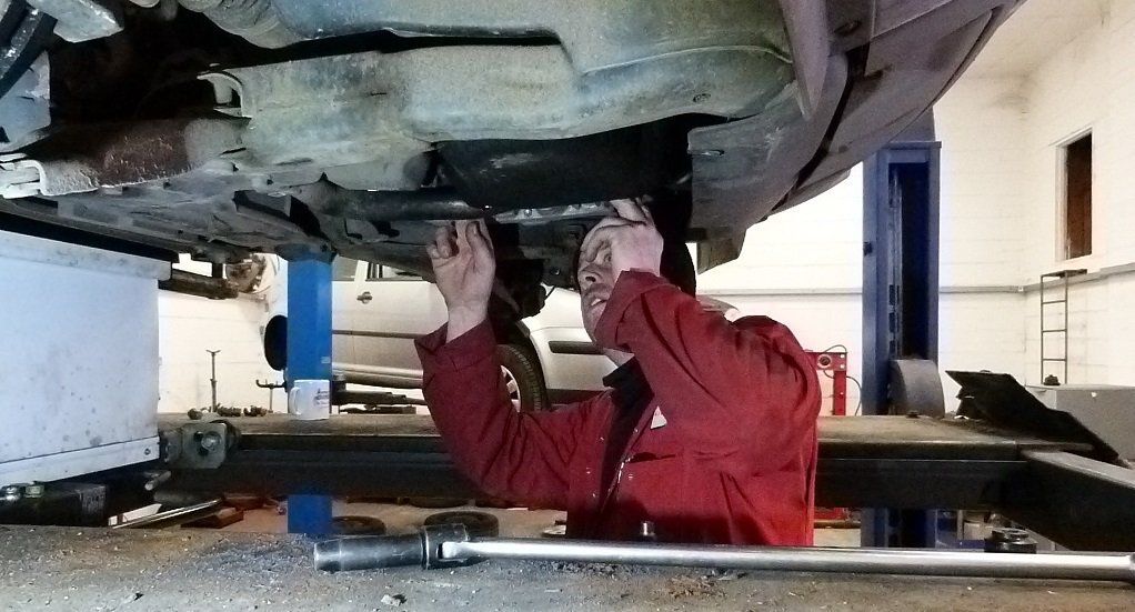Technician inspecting the underside of a car on a lift